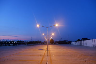 Illuminated street lights against blue sky