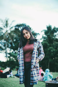 Portrait of young woman standing against trees