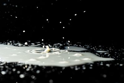 Close-up of drop falling on water against black background