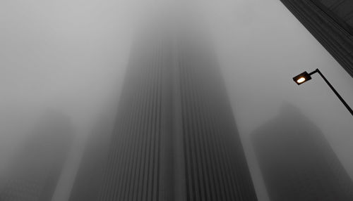 Low angle view of skyscrapers in foggy weather