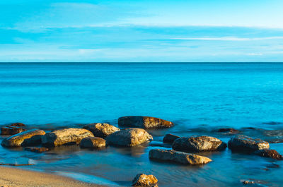 Rocks on sea shore against sky