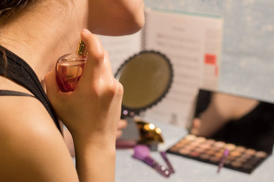 Midsection of woman applying perfume on neck during sunny day