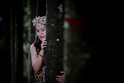 Portrait of young woman standing against wall