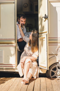 Camping and travelling. happy couple relaxing outdoors near trailer man and woman on their road trip