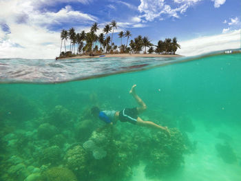 Man swimming undersea against sky