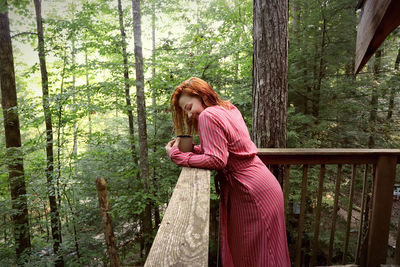 Side view of woman standing in forest