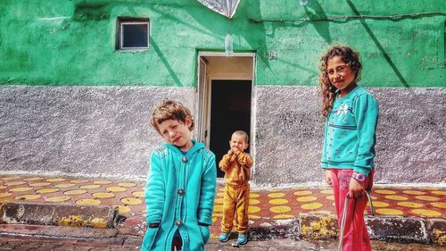 Full length of smiling girl standing against building