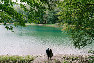 Rear view of men by lake in forest