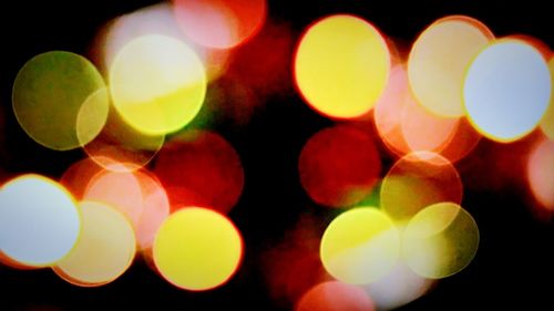 Defocused image of illuminated lights against black background