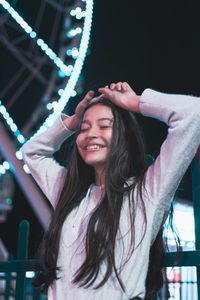 Portrait of smiling young woman standing at night