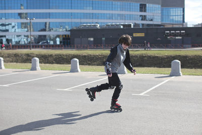 Teenage girl inline skating at parking lot in city