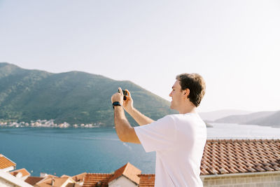 Side view of woman photographing against clear sky