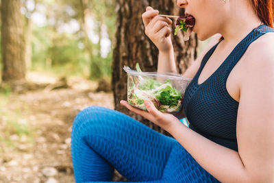 Young woman eating salad in forest