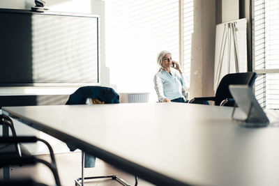 Businesswoman talking on smart phone sitting in board room