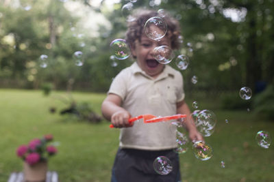 Boy playing with bubbles at park
