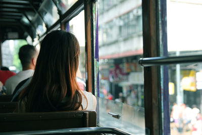 Rear view of woman looking through window