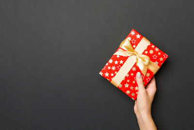 Cropped hand holding christmas present on black background