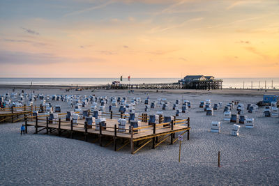 Chairs on beach against sky during sunset