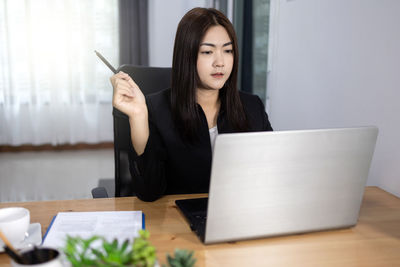 Young woman using phone while sitting on table