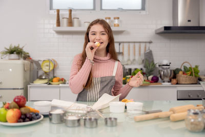 Portrait of young woman holding food at home