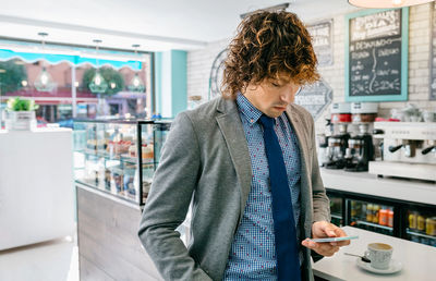 Businessman using phone while standing in cafe