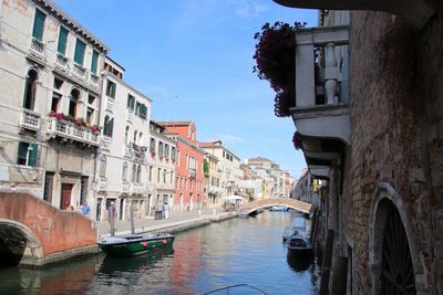 Canal amidst buildings in city against sky