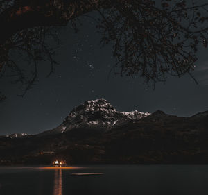 Scenic view of lake by mountains against sky at night