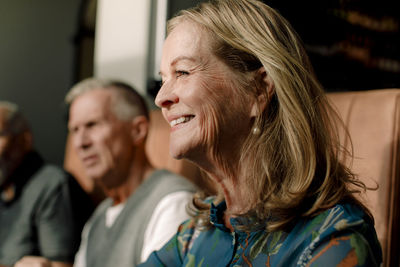 Happy senior blond woman with male friends at cafe