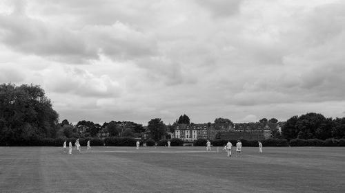 People playing soccer on field against sky