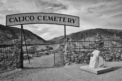 Cemetery sign on landscape against cloudy sky in ghost town in america