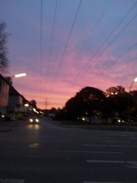 Cars on road against sky at sunset