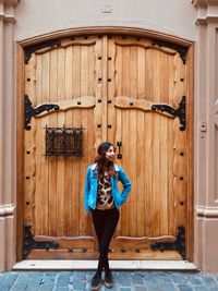 Full length of woman standing against door