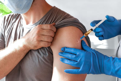 Hands of doctor injecting coronavirus covid-19 vaccine in  syringe to arm muscle of man for covid