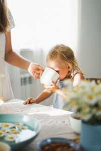 Mid section of mother feeding girl at home