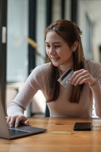 Young woman using mobile phone at table