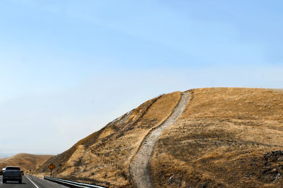 Road leading towards mountain against clear blue sky