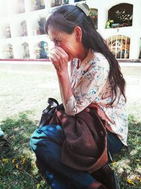 Midsection of woman with girl sitting outdoors