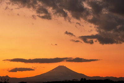 Scenic view of silhouette mountains against orange sky