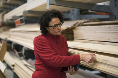 Female customer selecting wooden plank at hardware store