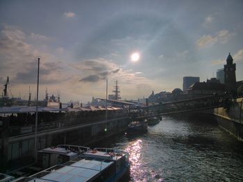 River amidst buildings in city against sky during sunset