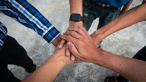 High angle view of people stacking hands outdoors