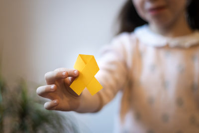 The girl is holding a yellow ribbon in her hands.