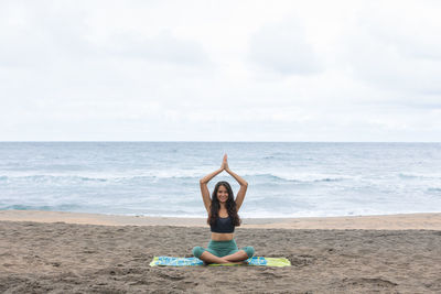 Lady sitting in lotus asana and meditating on beach