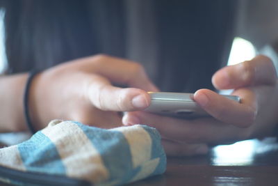 Midsection of woman using mobile phone on table