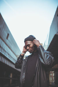 Low angle view of man listening music against sky