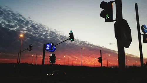 Silhouette road sign against sky during sunset