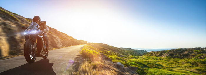 Man cycling on mountain against clear sky