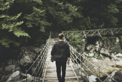 Rear view of man walking on footbridge