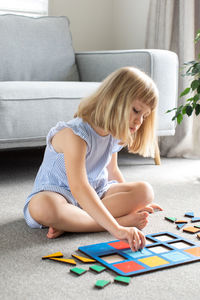 Girl playing with toy while sitting on sofa at home