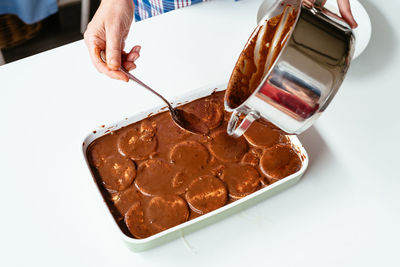 Midsection of man pouring chocolate syrup in cookies on table